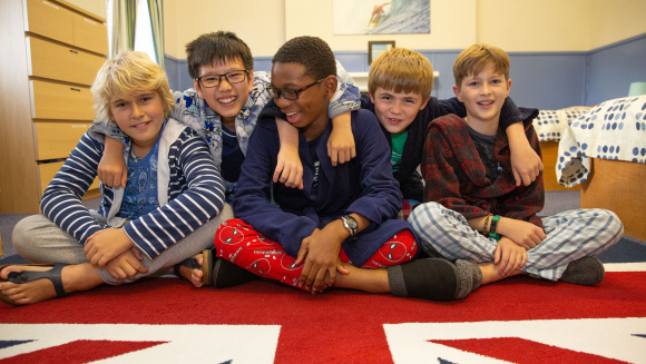Boarders at Lockers Park School in their pyjamas, dressing gowns and sitting on a Union Flag rug