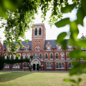 A view, framed by tree leaves of the main building of Emanuel School