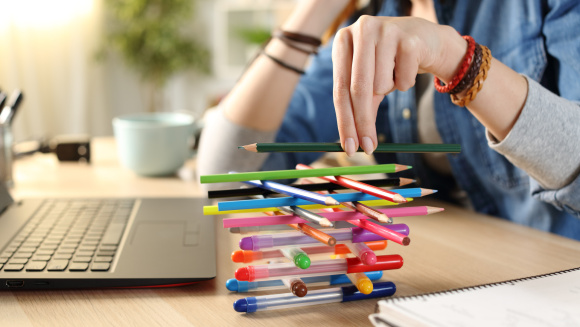 A photo of a teenager stacking pens and pencils