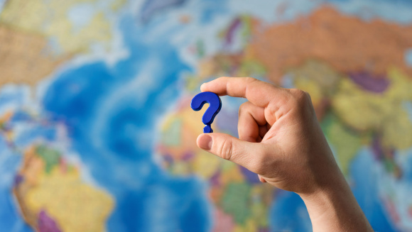 A question mark in front of a map of the world