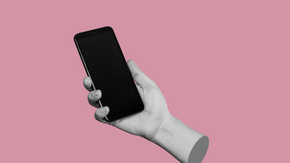 A hand holding a smart phone on a pink background