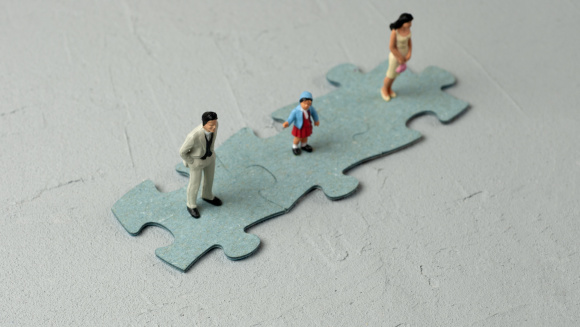 A family of minitures standing on jigsaw puzzle pieces